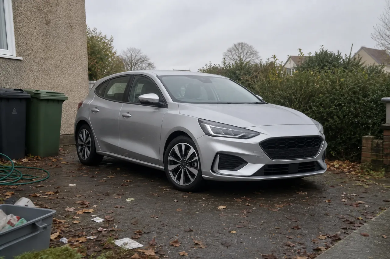The same silver hatchback as a messy phone snap on a cluttered driveway